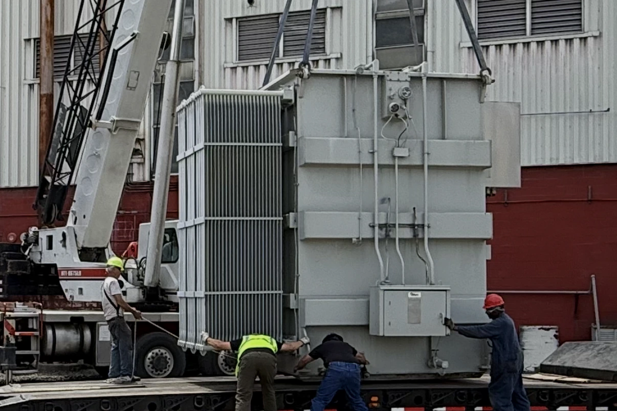 Crane lifting a power transformer onto a lowboy trailer while the removal crew guides the load — Springfield, MO